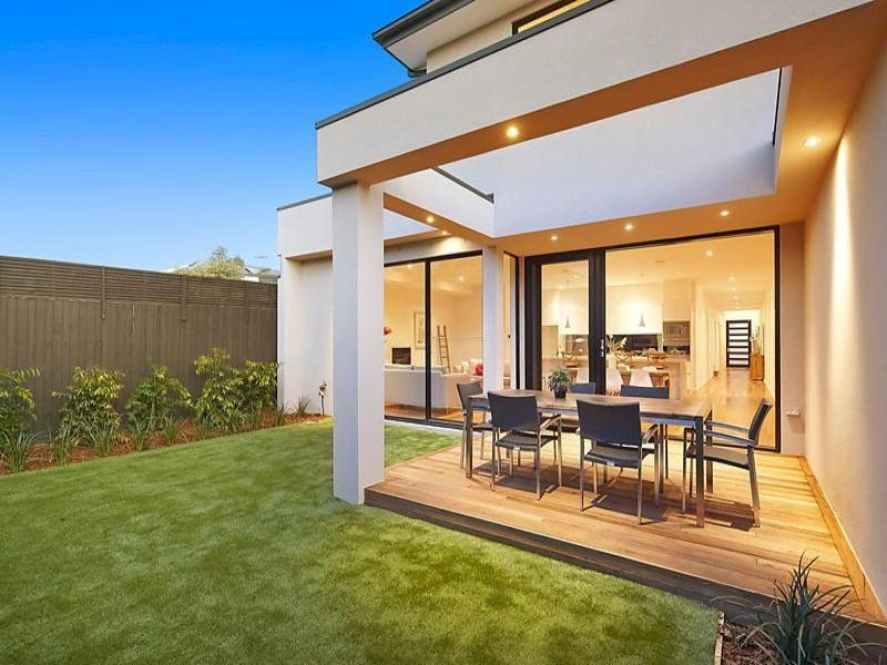 A patio with a table and chairs in the backyard of a house