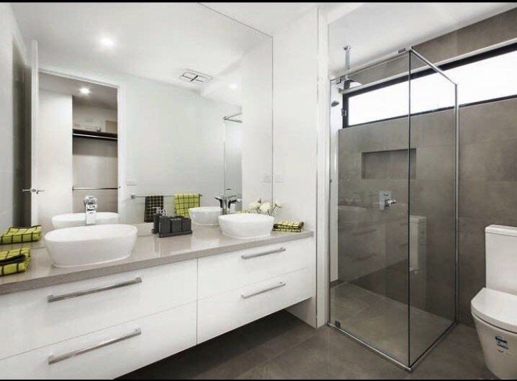 A bathroom with two sinks , a toilet and a walk in shower.