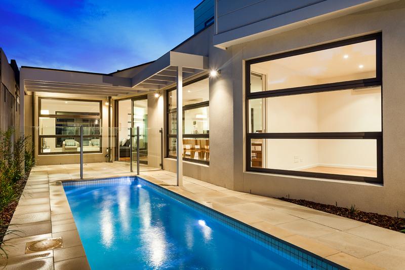 A large swimming pool is in the backyard of a house.