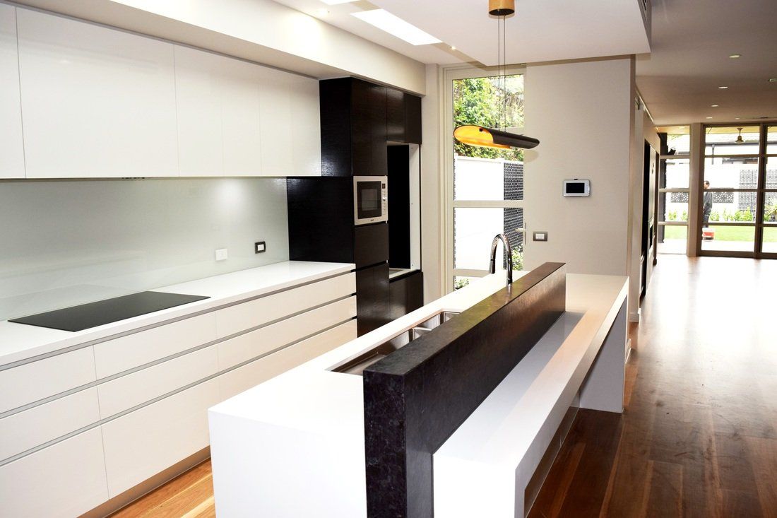 A kitchen with white cabinets and a black refrigerator