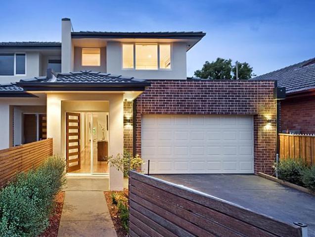 The front of a house with a white garage door and a wooden fence.