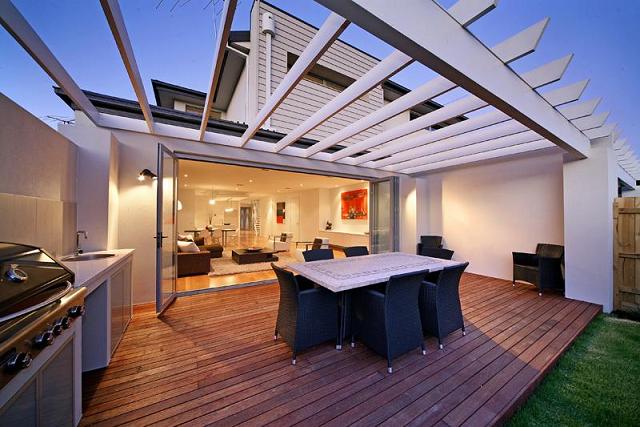 A wooden deck with a table and chairs under a pergola