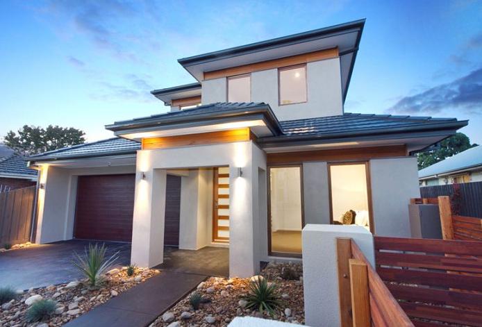 A large white house with a red garage door is lit up at night.