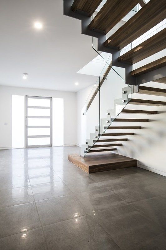 An empty room with a staircase and a glass railing.