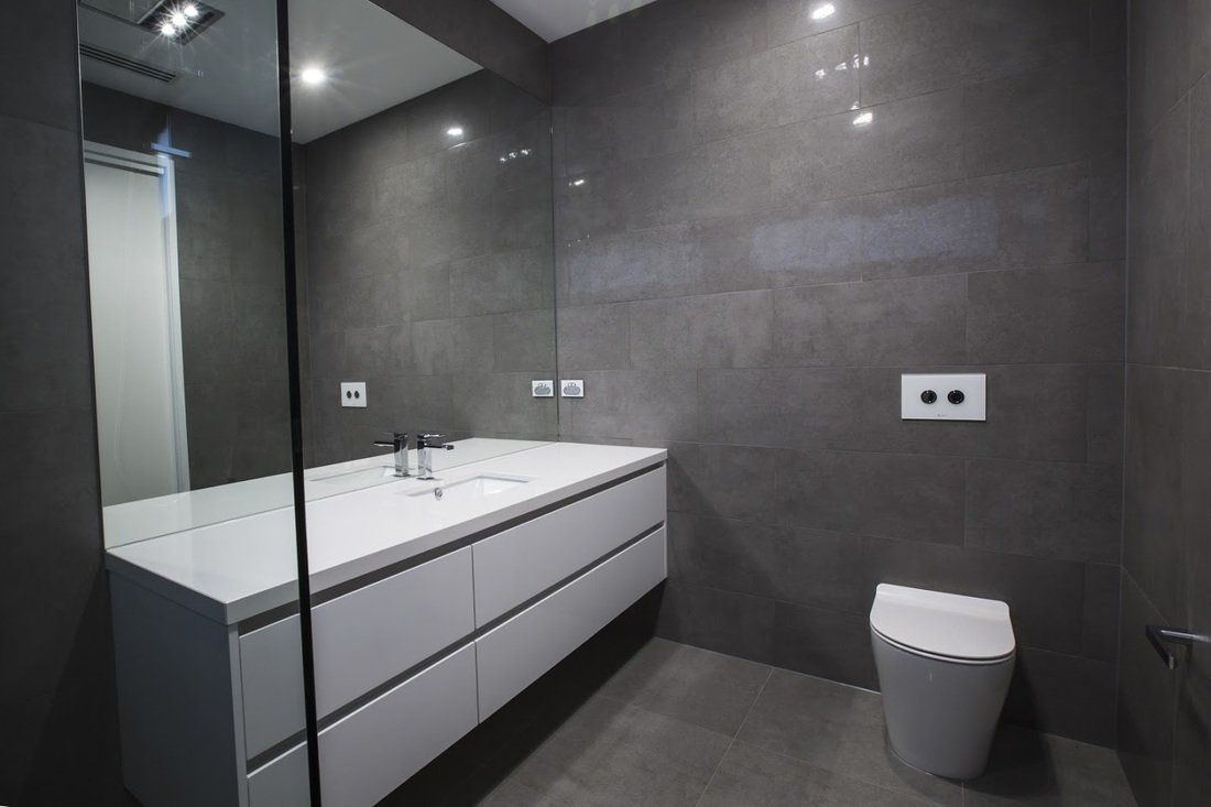 A bathroom with a sink , toilet and mirror.