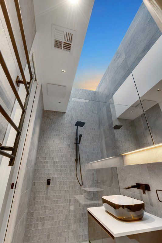 A bathroom with a sink and a shower with a skylight in the ceiling