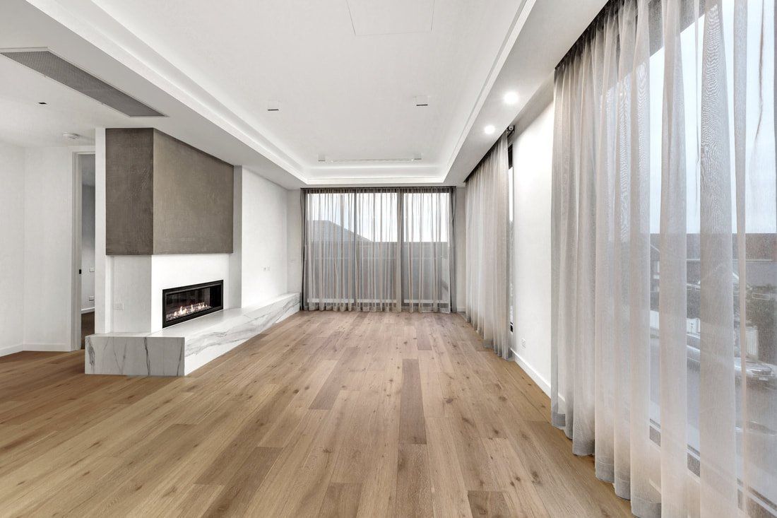 An empty living room with hardwood floors and a fireplace.