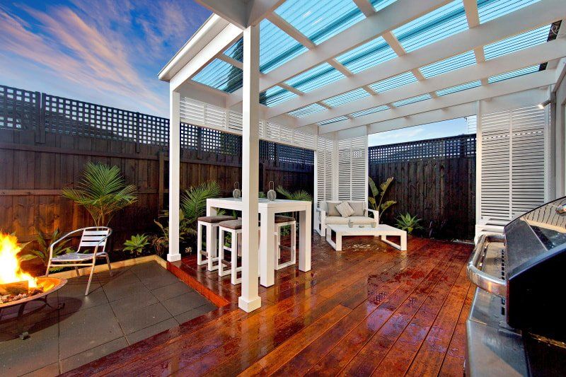 A patio with a fire pit and a table and chairs under a pergola.