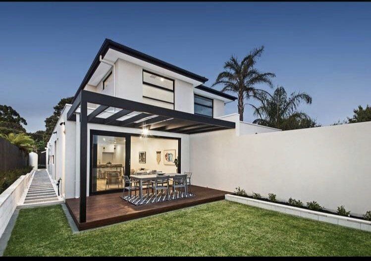The backyard of a house with a pergola and a table and chairs