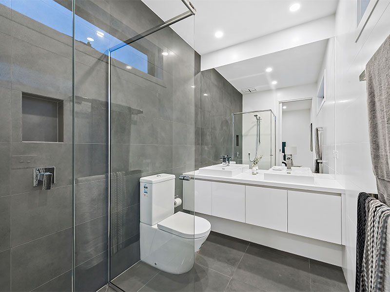 A bathroom with a toilet , sink and walk in shower.