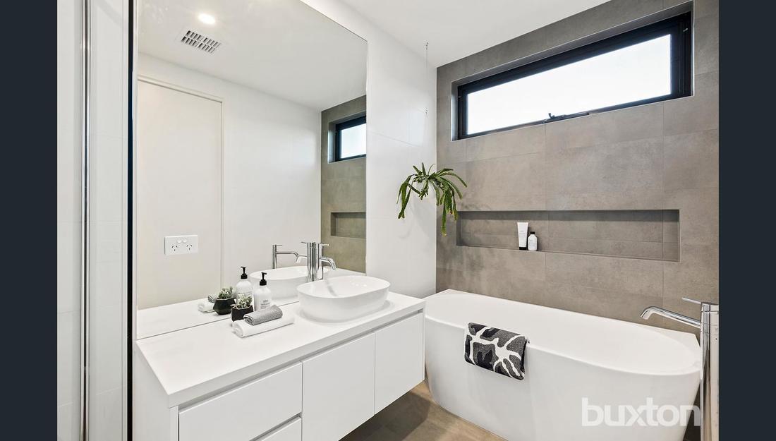 A bathroom with a tub , sink , mirror and window.
