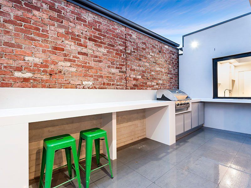 A kitchen with a brick wall and green stools