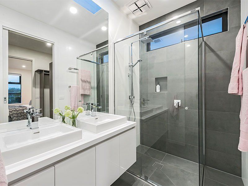 A bathroom with two sinks and a walk in shower.