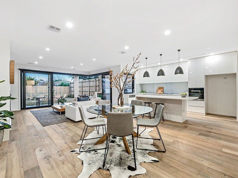A living room with a dining table and chairs and a cowhide rug on the floor.