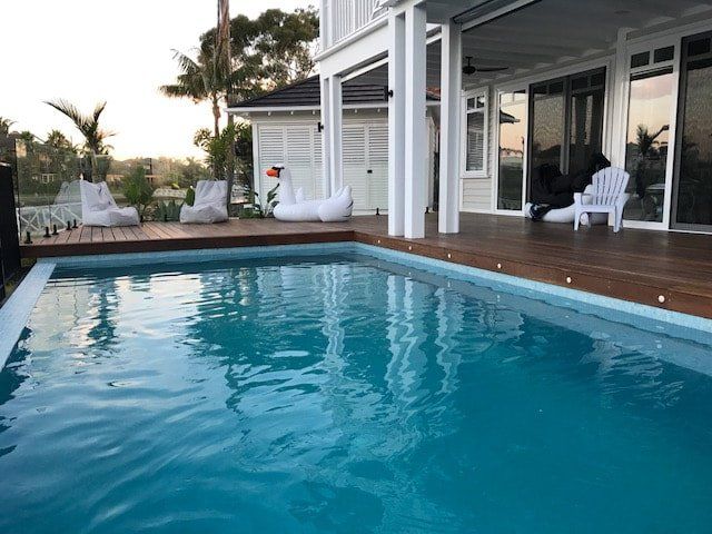 A large swimming pool in front of a white house
