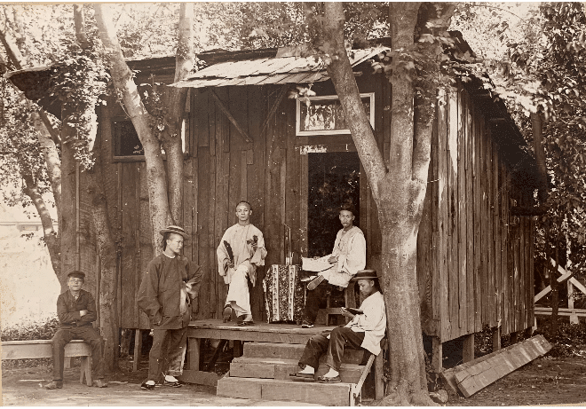 Five Chinese men sit on the front porch of the Chinatown Lai Hing Co. Store. 