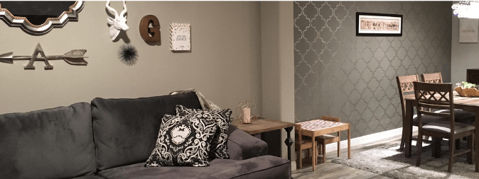 Inside a Las Vegas Home purchased with an FHA Home Loan shows couch, dining table and accent wall in modern gray and wood colors