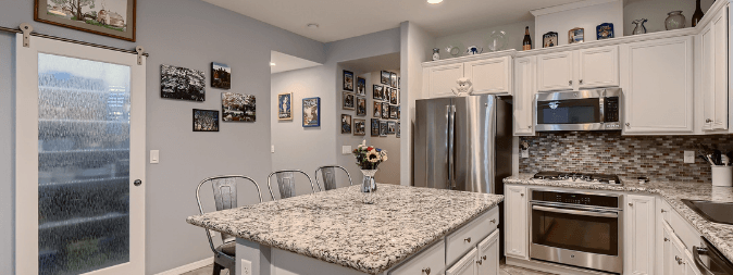 Kitchen and pantry of a home refinanced in Las Vegas shows island and granite countertops and stainless steel appliances