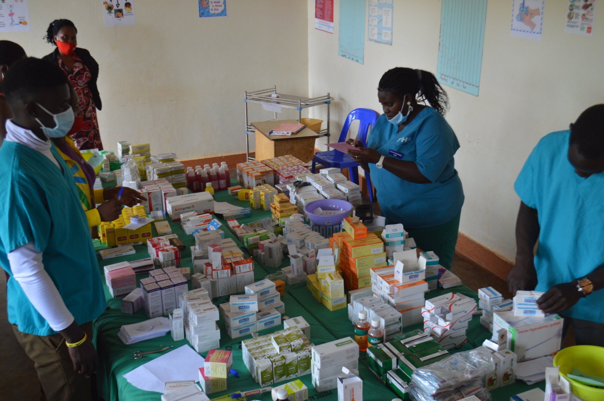 Medical professionals sort medications on a table in a clinic setting.
