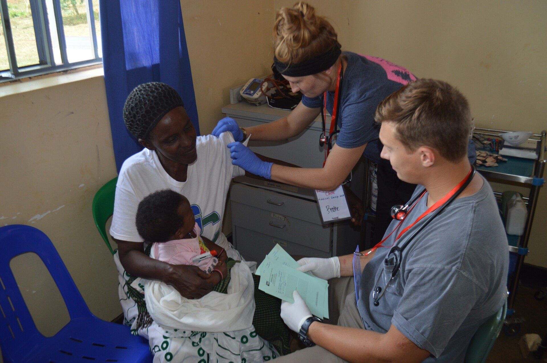 Medical staff administering a shot to a woman holding a baby in a clinic.
