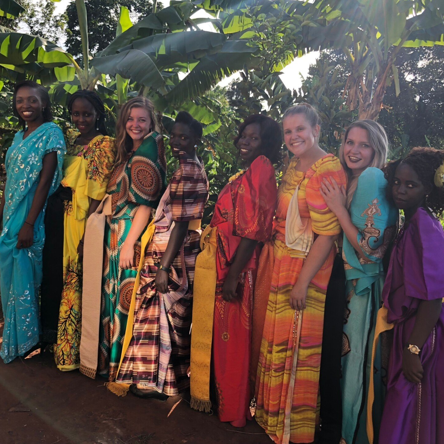 Group of women in colorful dresses standing outdoors.