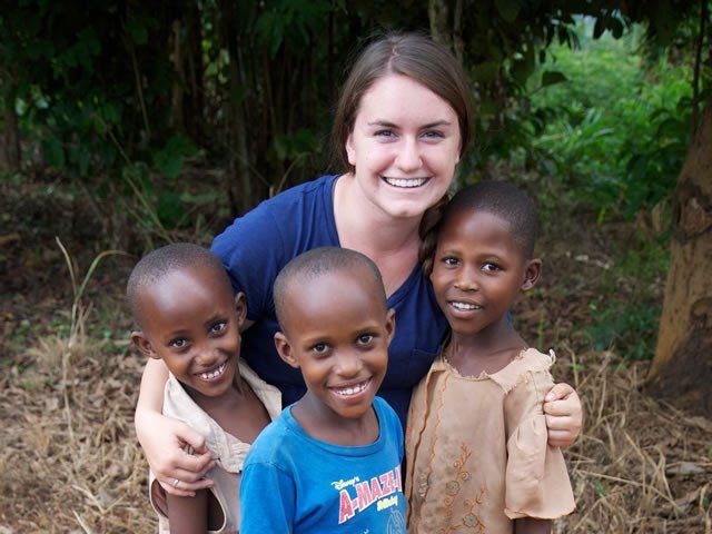 Woman smiling with three smiling children outdoors.