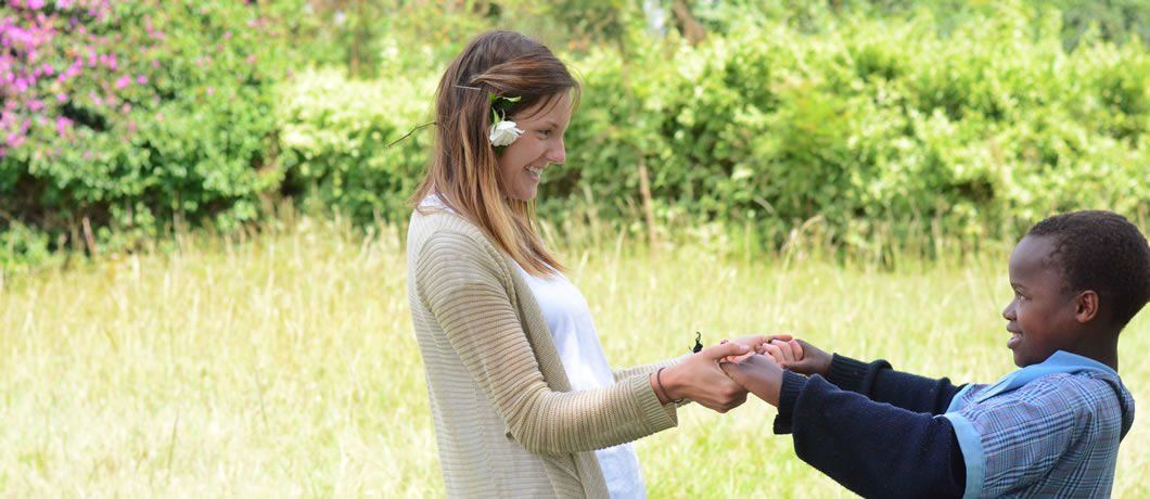 A woman and a boy are holding hands in a field.