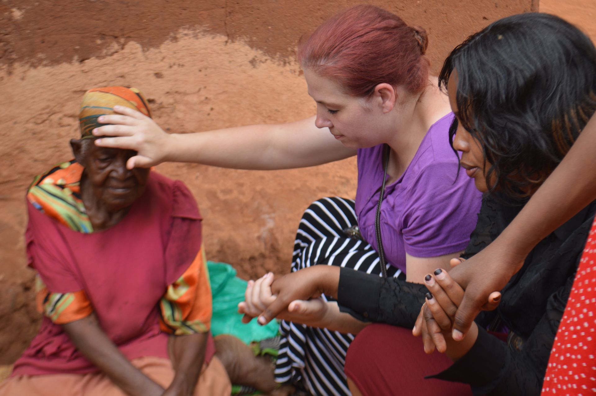 Group of people smiling near a thatched hut in a lush, green environment.