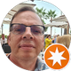 Ein Mann mit Brille und einem Stern in einem orangefarbenen Kreis.