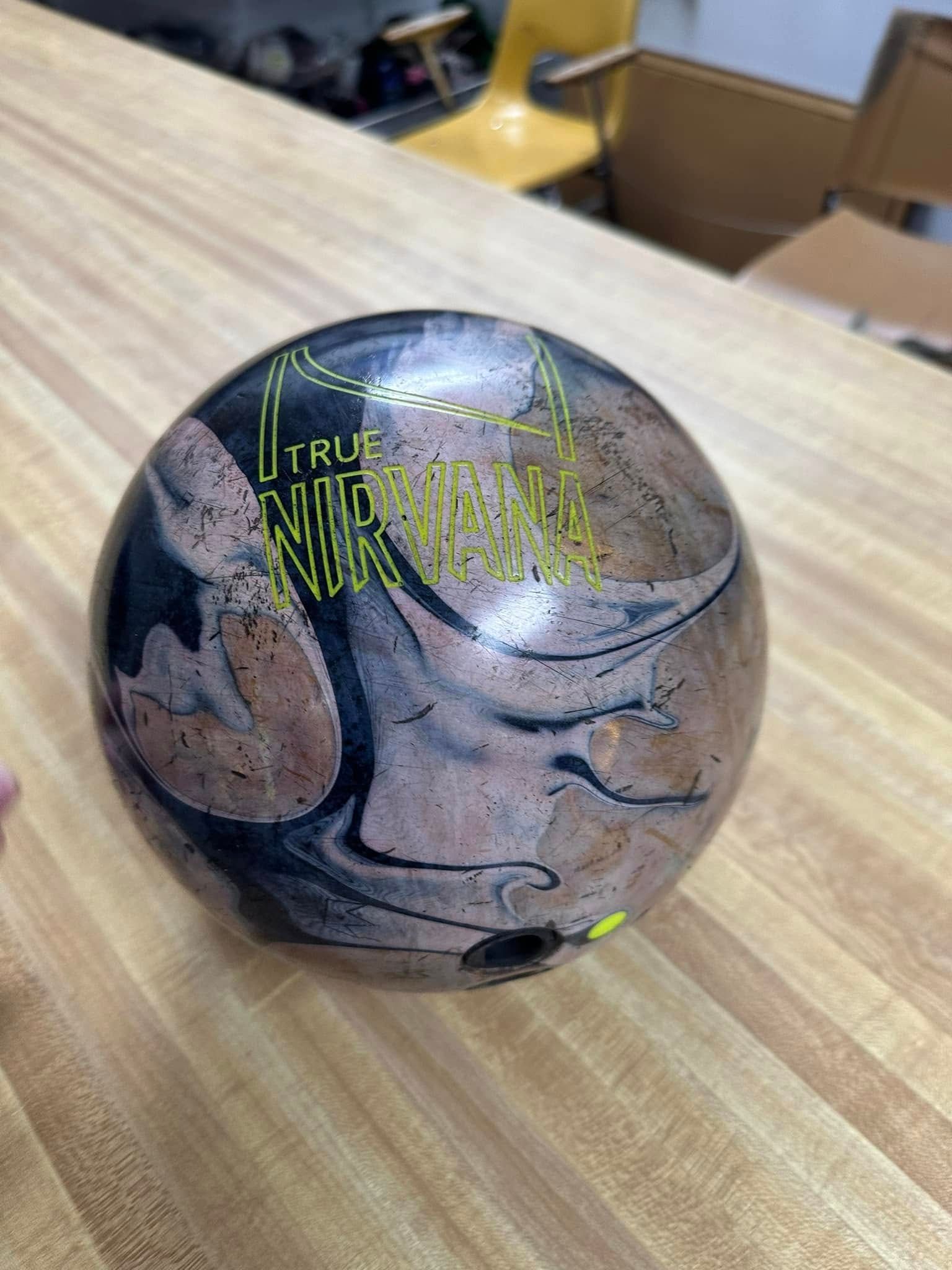 A bowling ball is sitting on top of a wooden table.