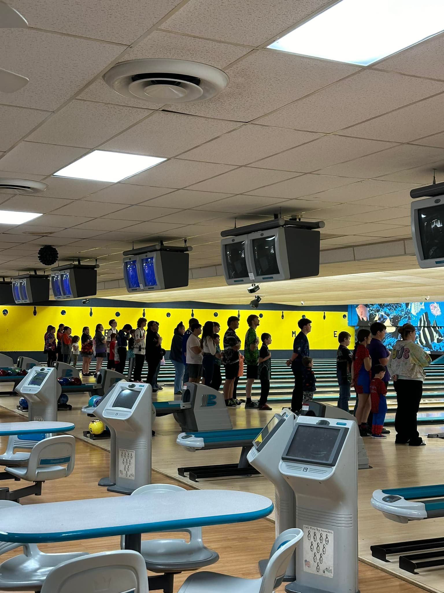 A group of people are standing in a bowling alley