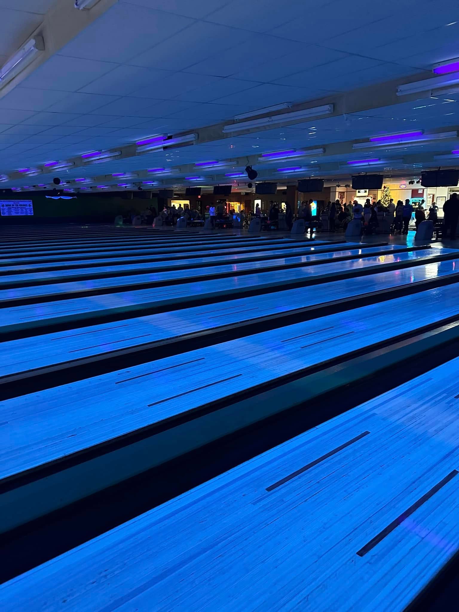 A bowling alley is lit up at night with blue lights.