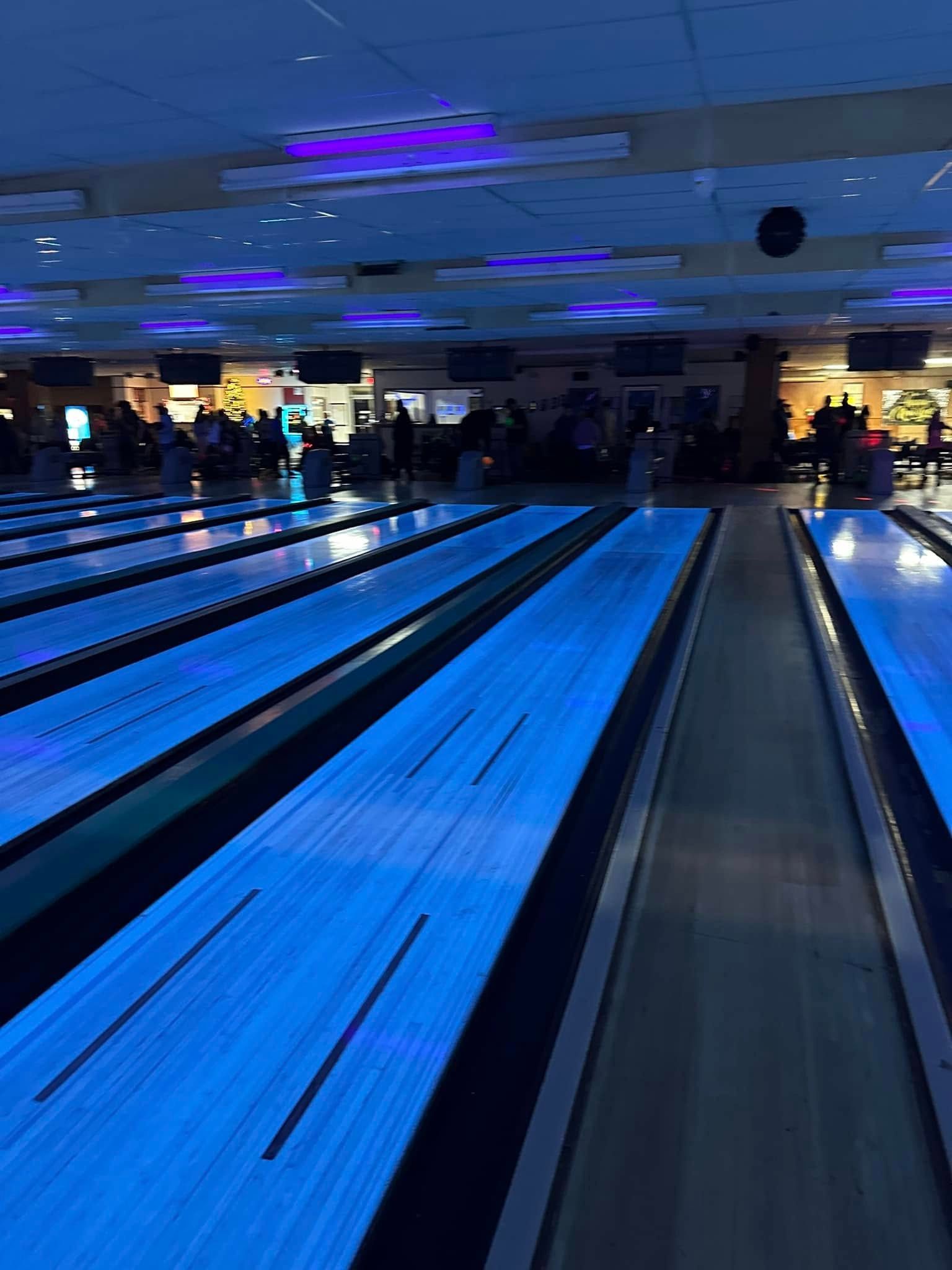 A bowling alley is lit up with blue lights at night.