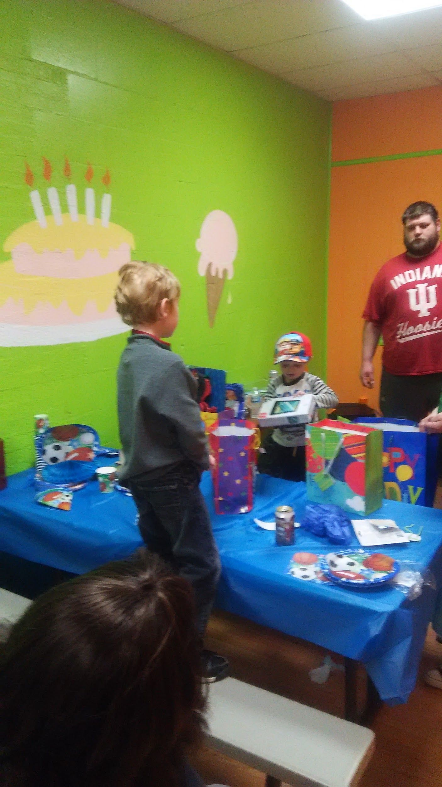 A group of children are standing around a table at a birthday party.