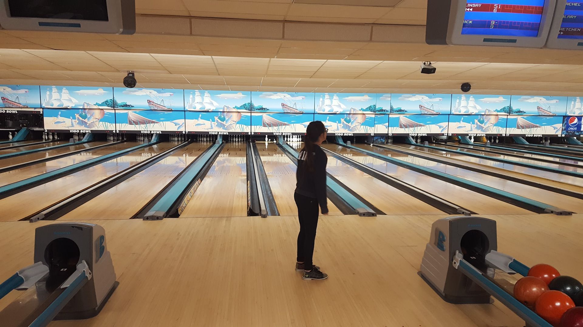 A person is standing in the middle of a bowling alley.