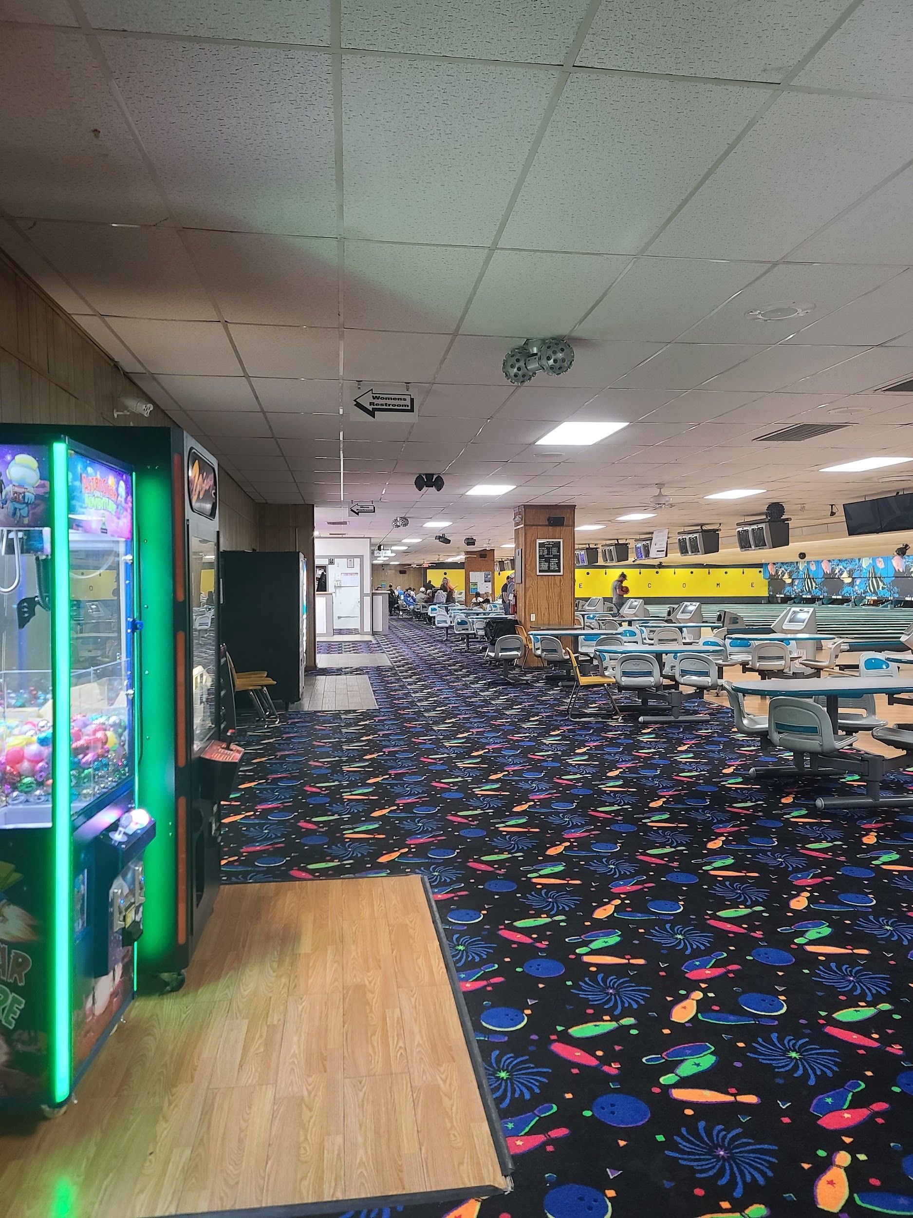 A bowling alley with a colorful carpet and a claw machine.