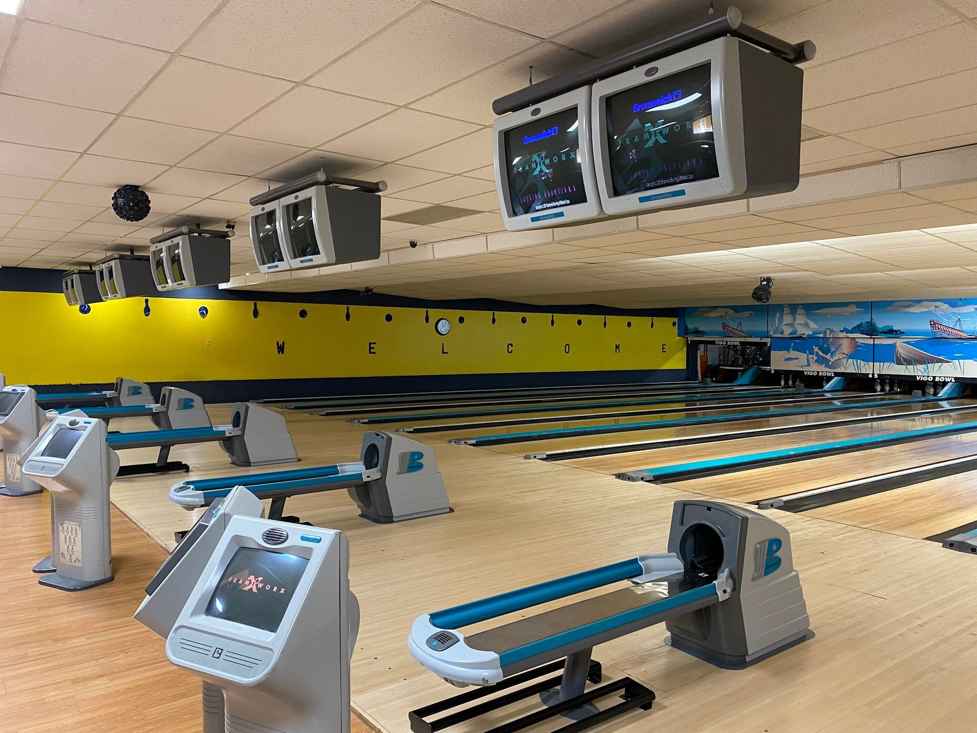 A bowling alley with a lot of bowling pins and televisions