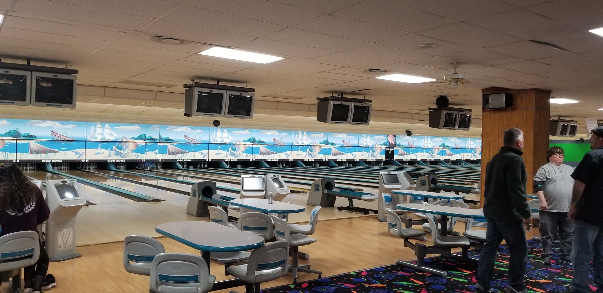 A group of people are standing in a bowling alley.