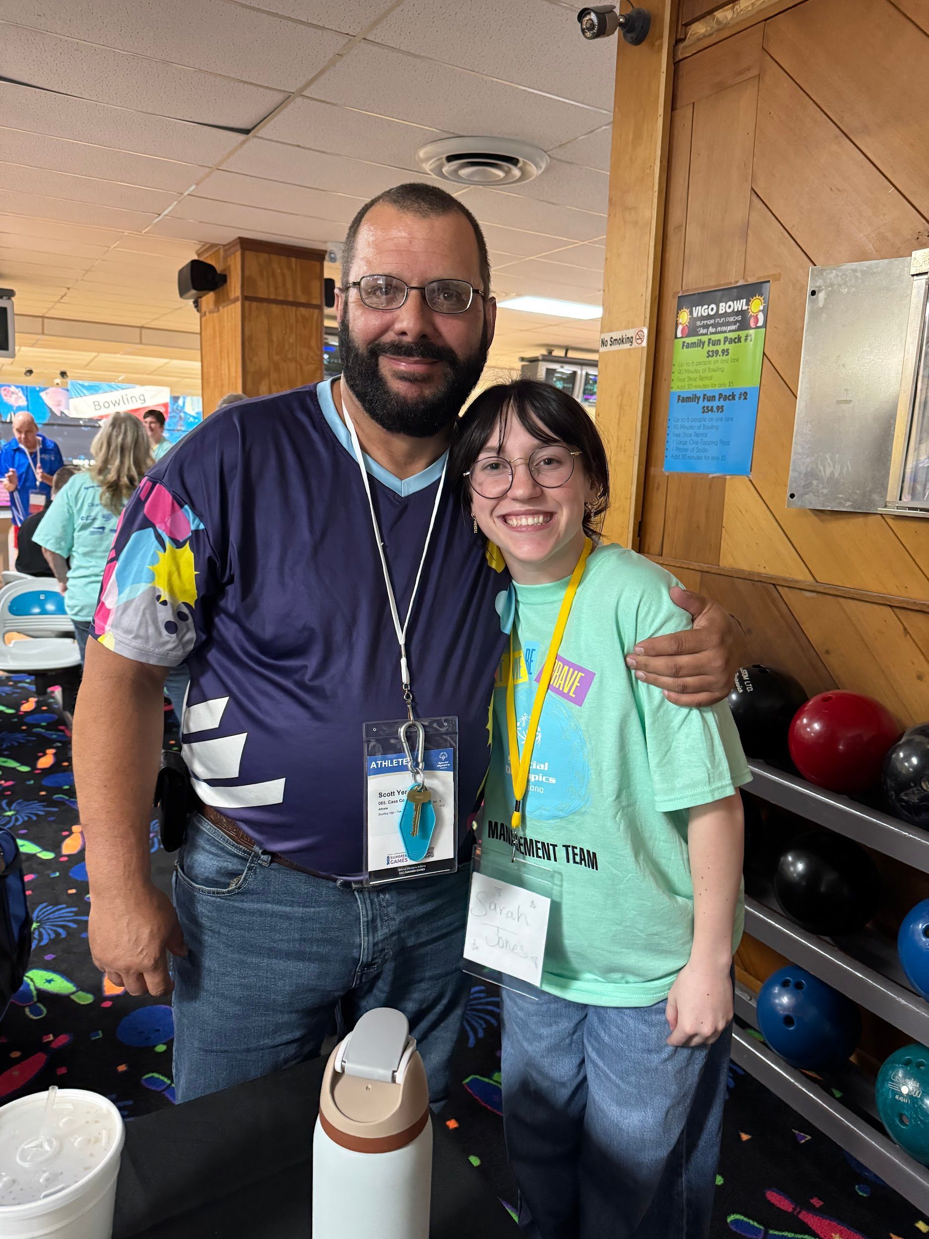 A man and a girl are posing for a picture in a bowling alley.