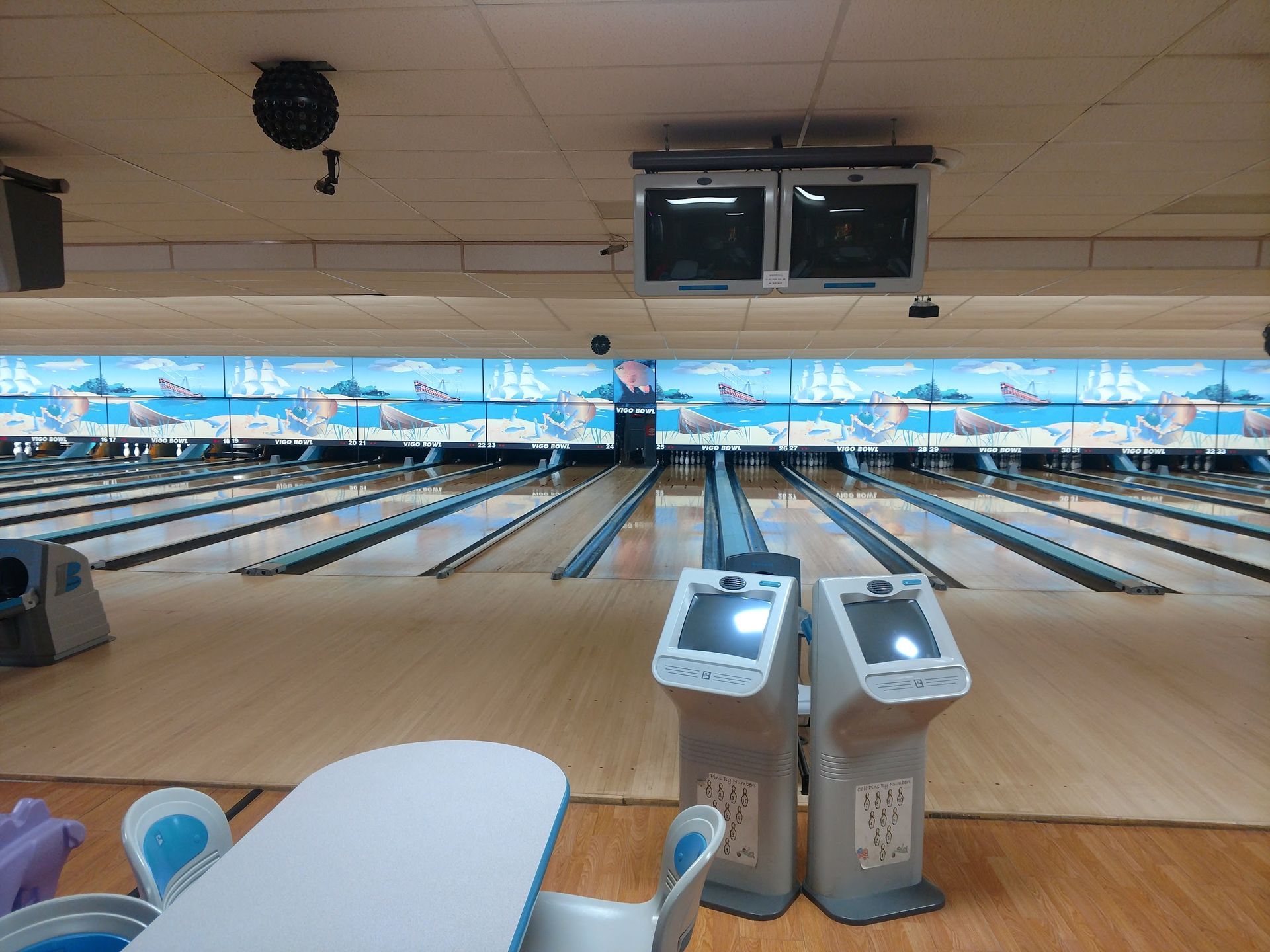 A bowling alley with a table and two kiosks