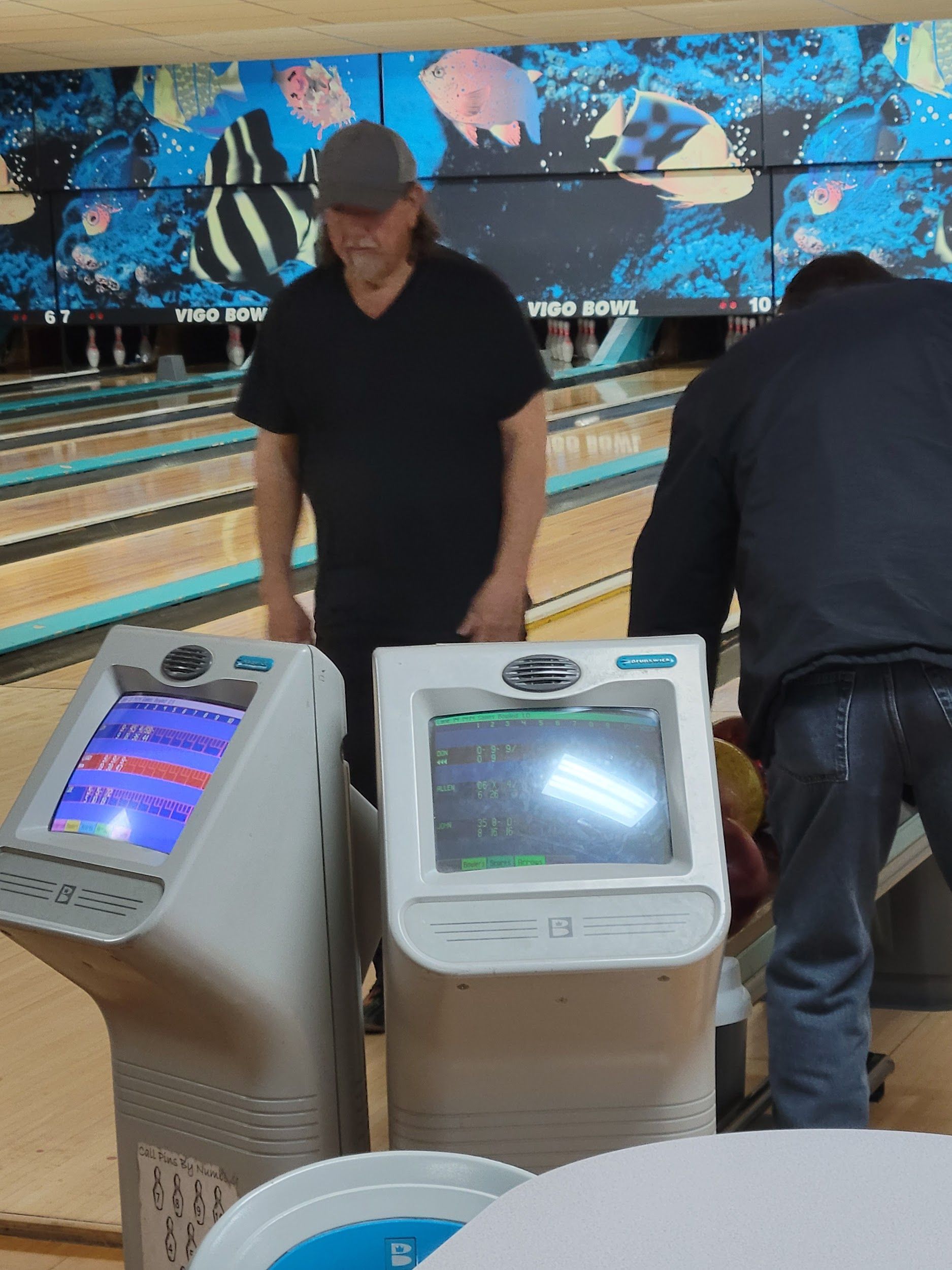 Two men are playing bowling in a bowling alley