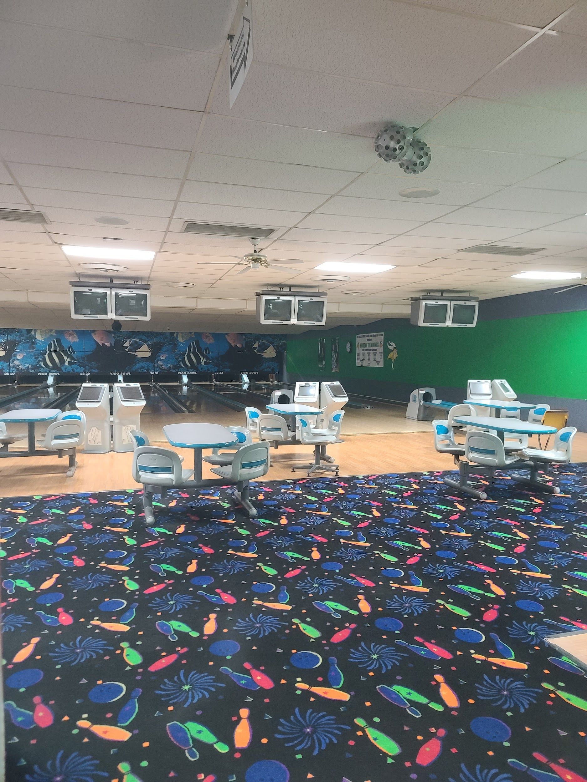 A bowling alley with tables and chairs and a colorful carpet