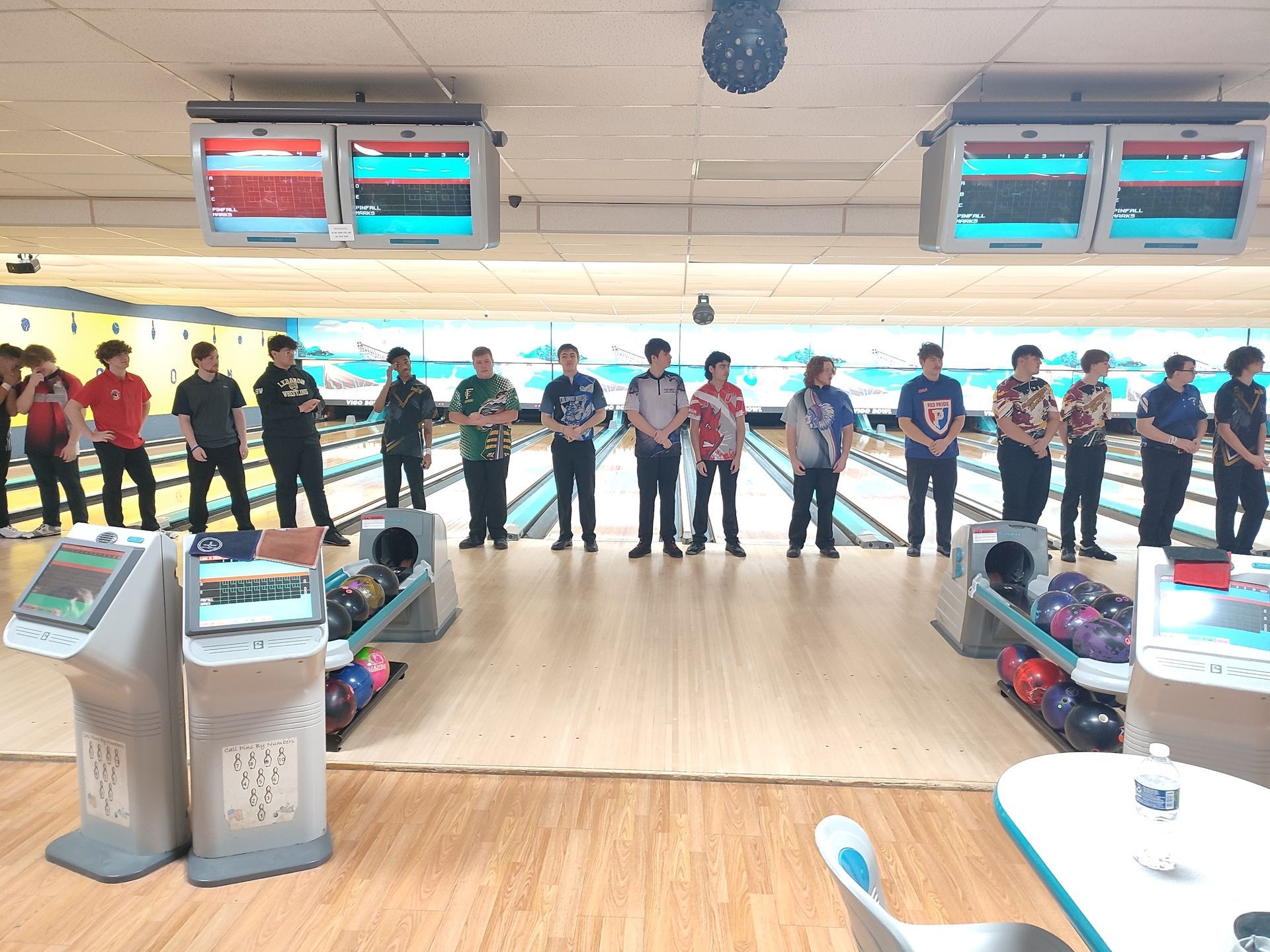 A group of people are standing in a bowling alley.