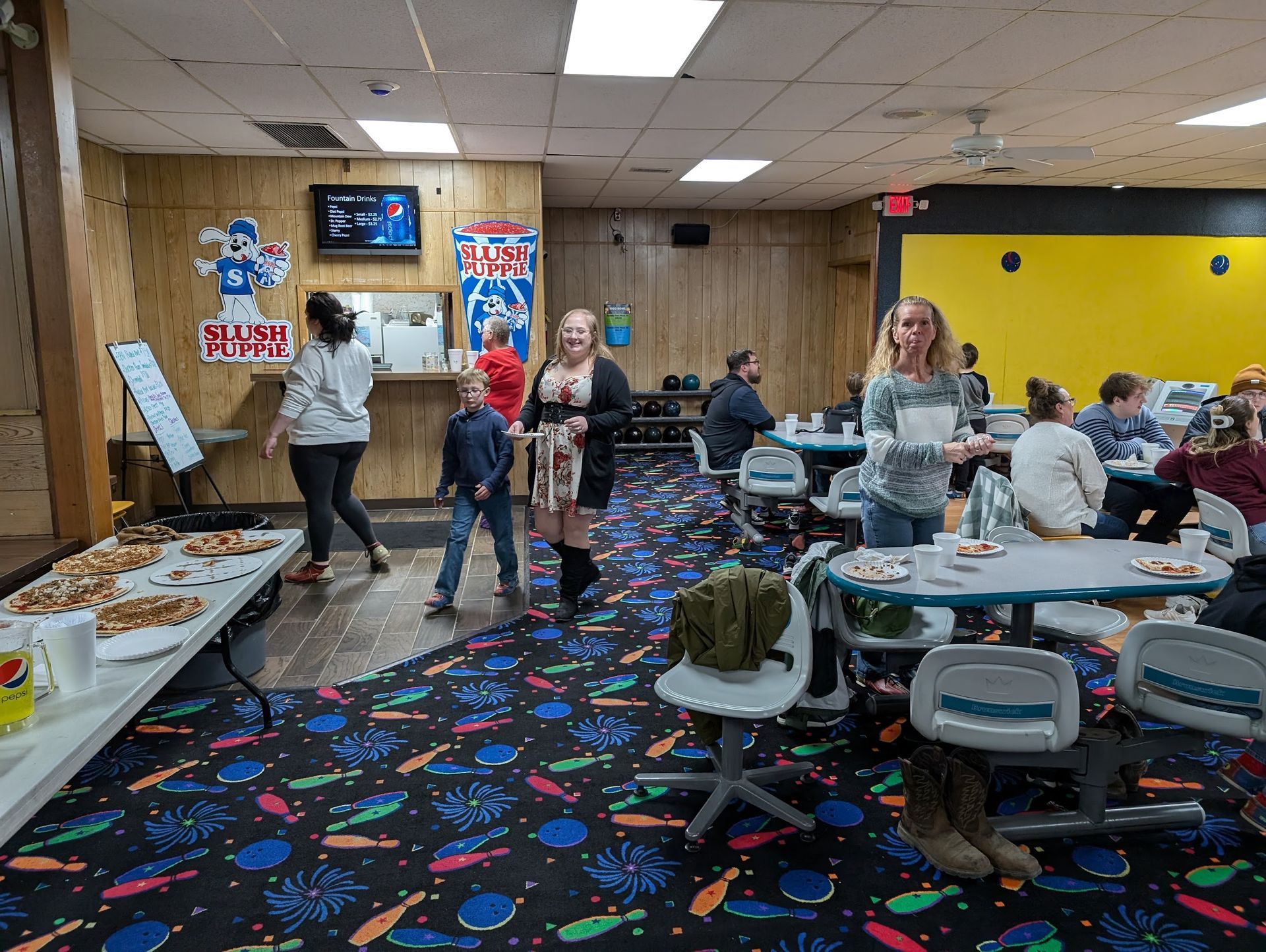 A group of people are standing in a bowling alley.