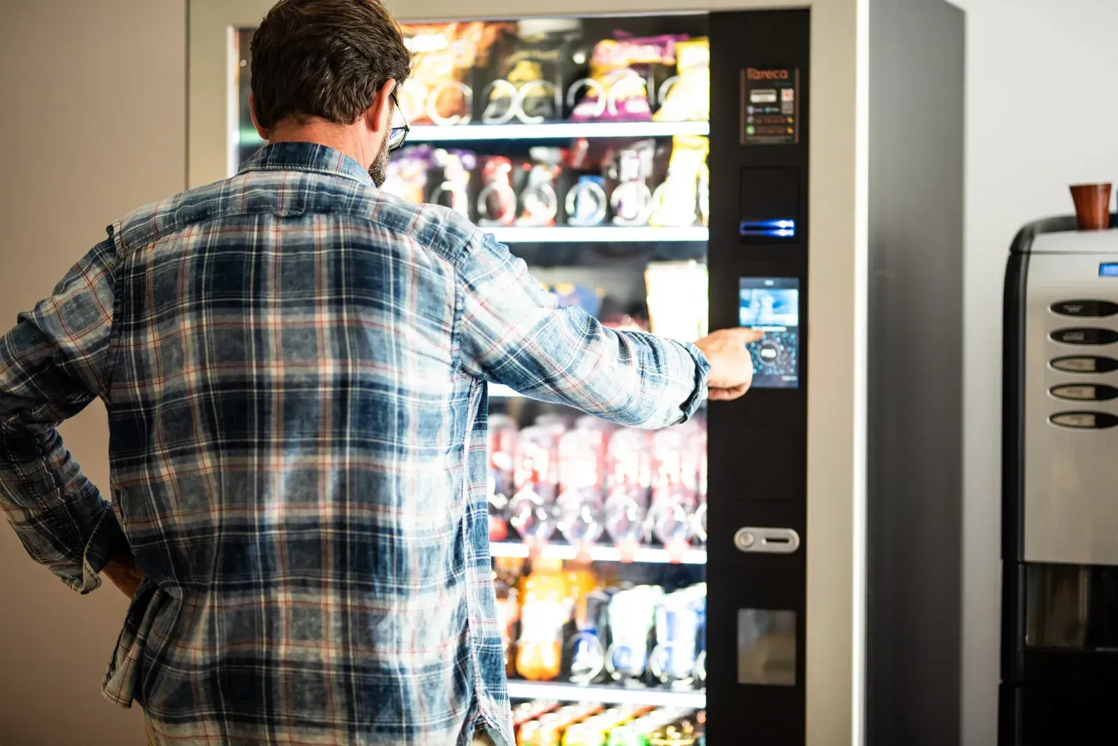 A man is standing in front of a vending machine.