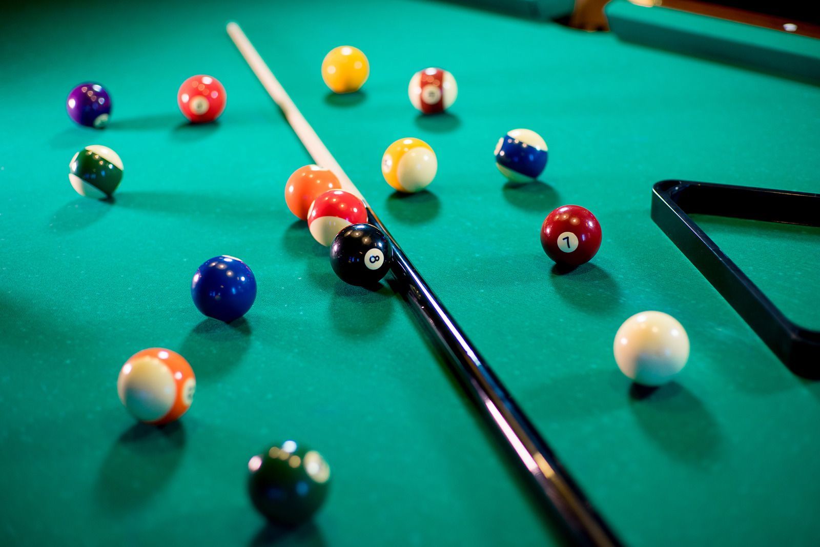 A pool table with pool balls and a cue on it.