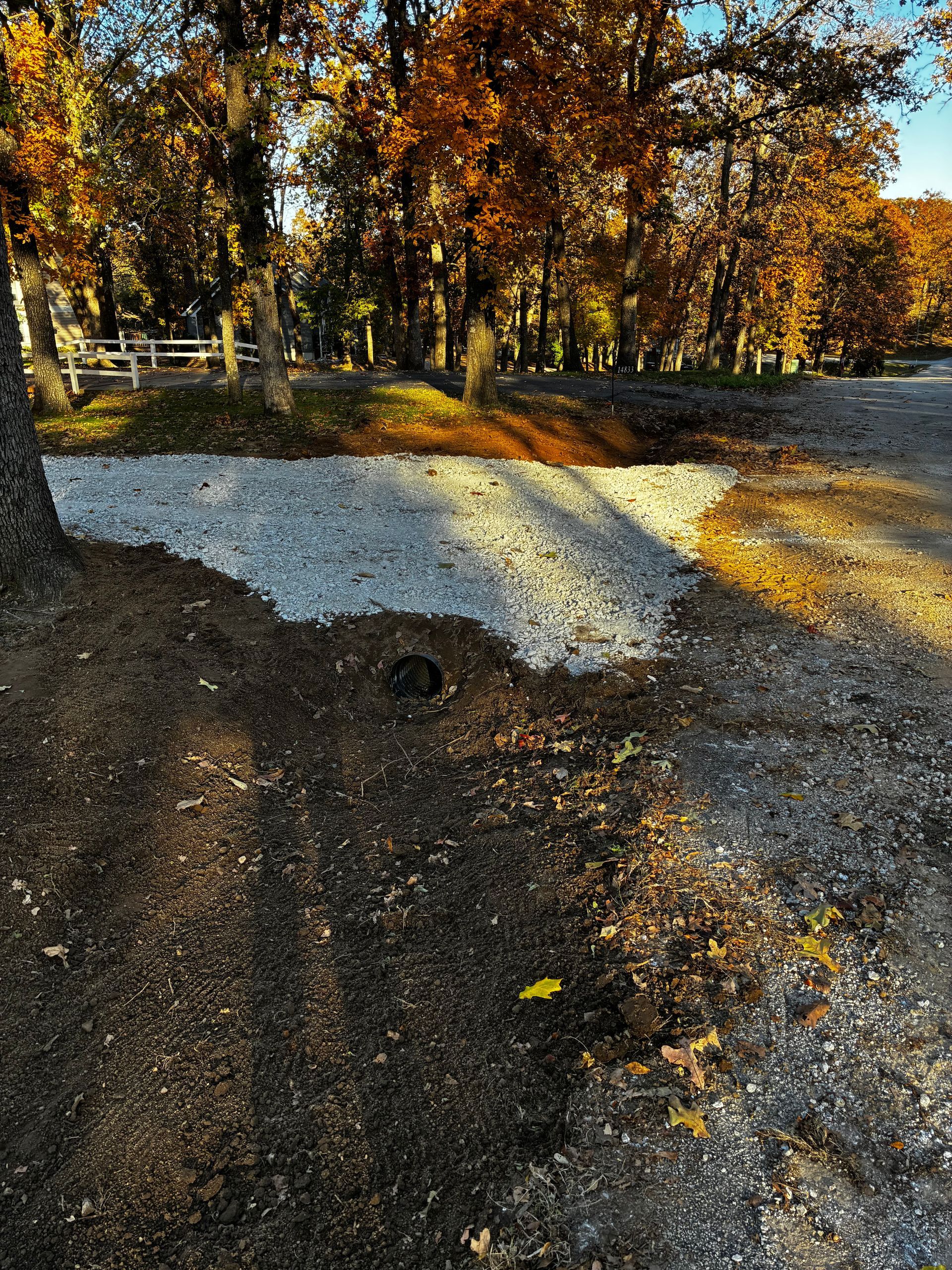 Gravel area next to dirt path. Autumn trees in the background.
