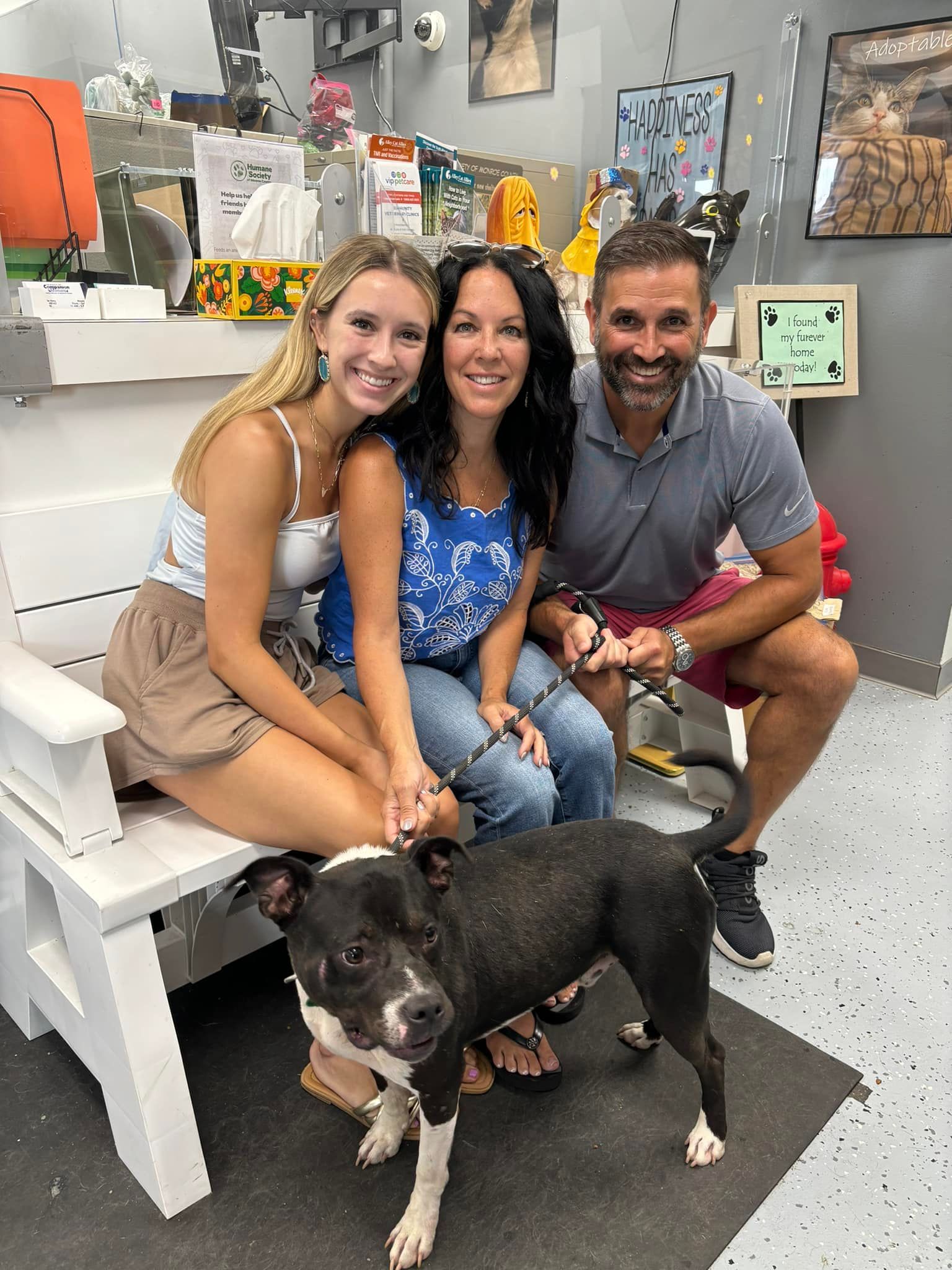 A group of people are sitting on a bench with a dog.