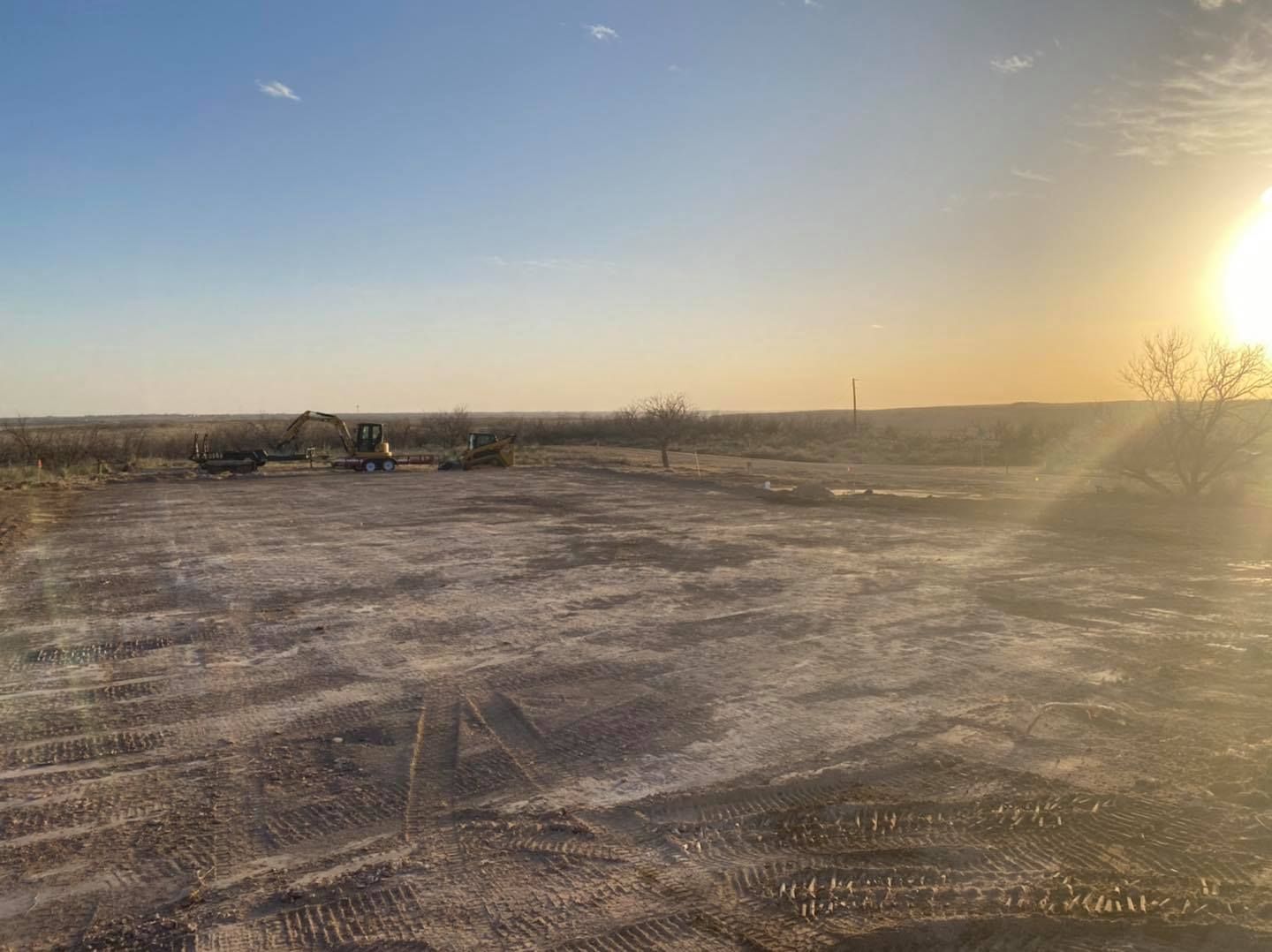 Open field with construction equipment; bright sun in the sky.