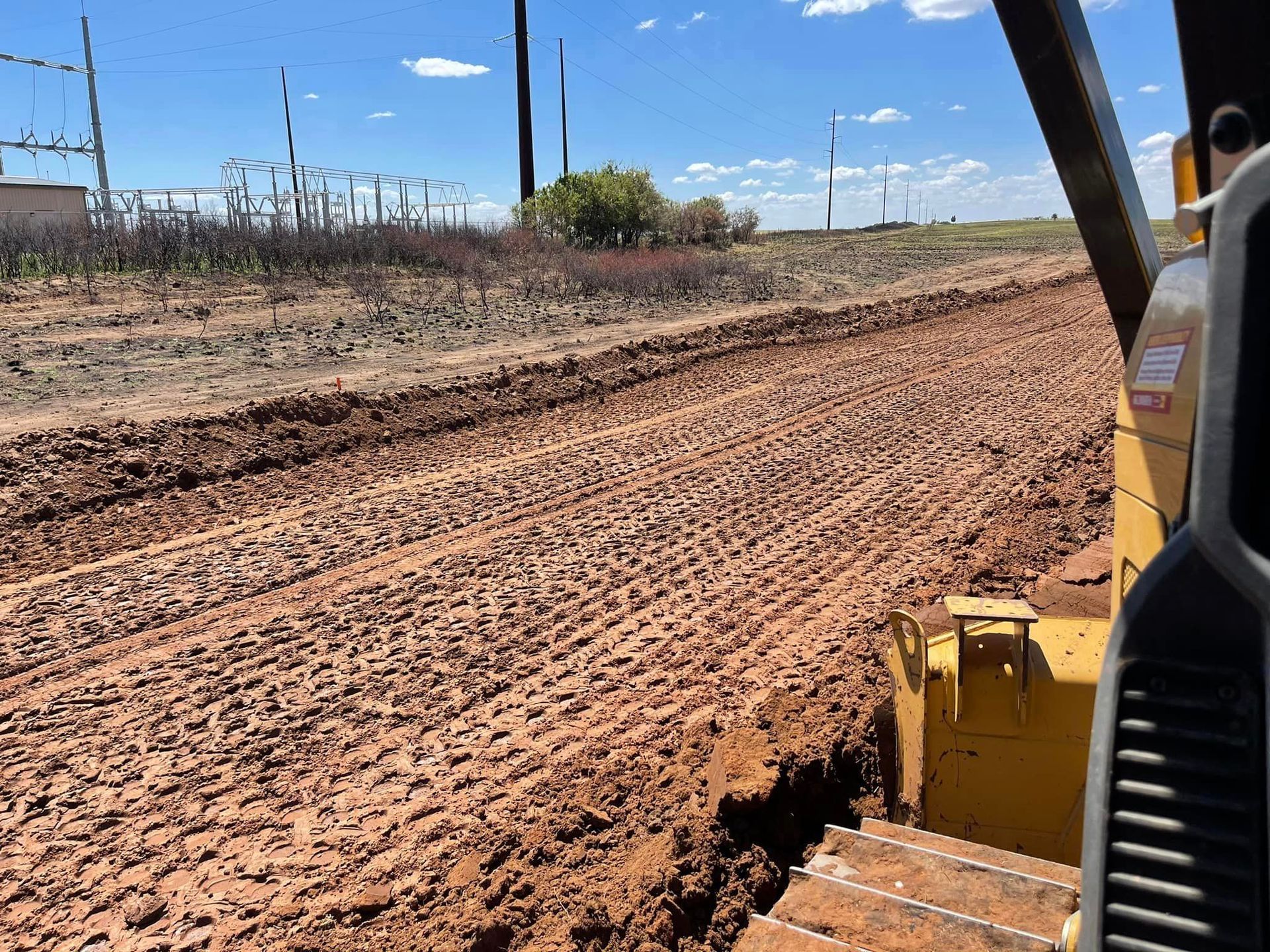 A bulldozer grading a muddy dirt road.